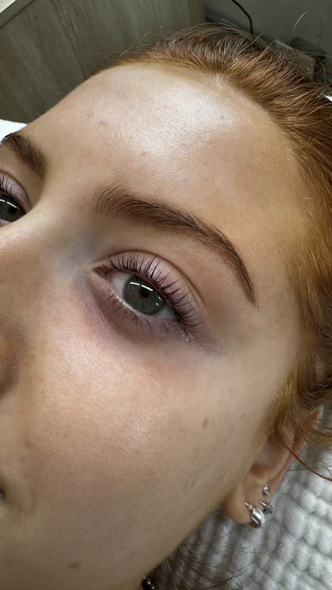 Close-up of curled natural lashes and a softly shaped brow beside a green eye